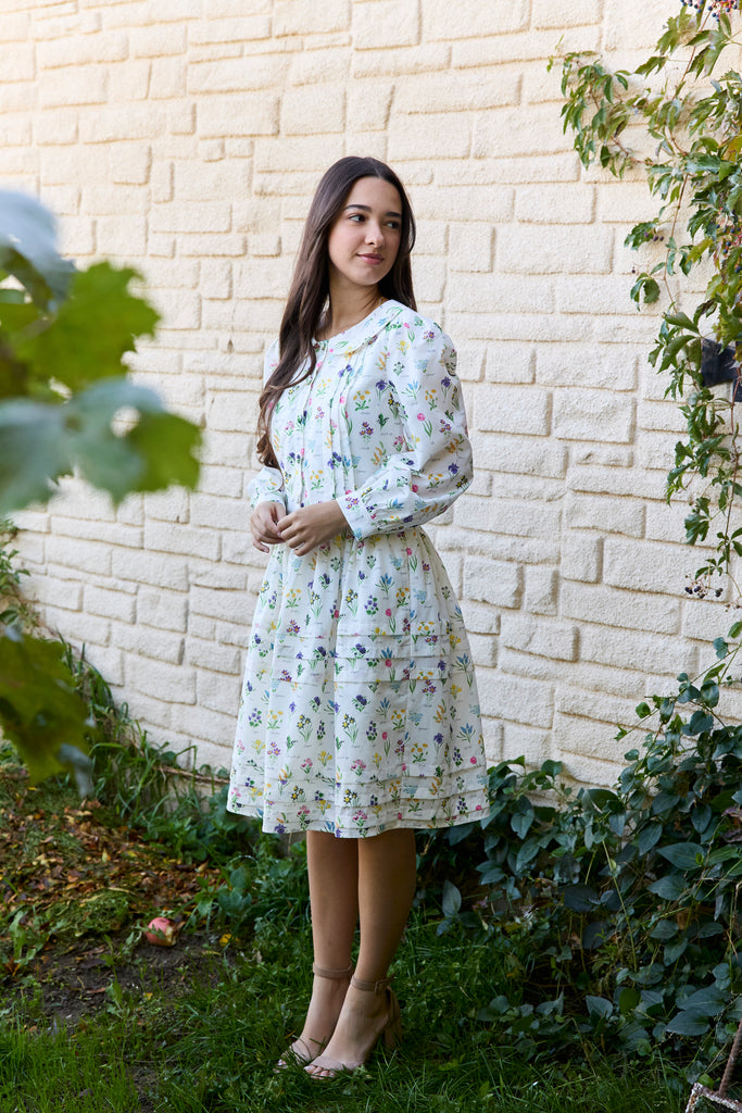 Woman in a floral dress standing in front of a brick wall with greenery - botanical peter pan collar floral cottagecore feminine spring easter outfit soft girl aesthetic outfit