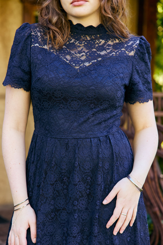 Navy lace dress worn by a woman with a blurred background - navy lace midi elegant romantic bridal shower church wedding guest outfit modest
