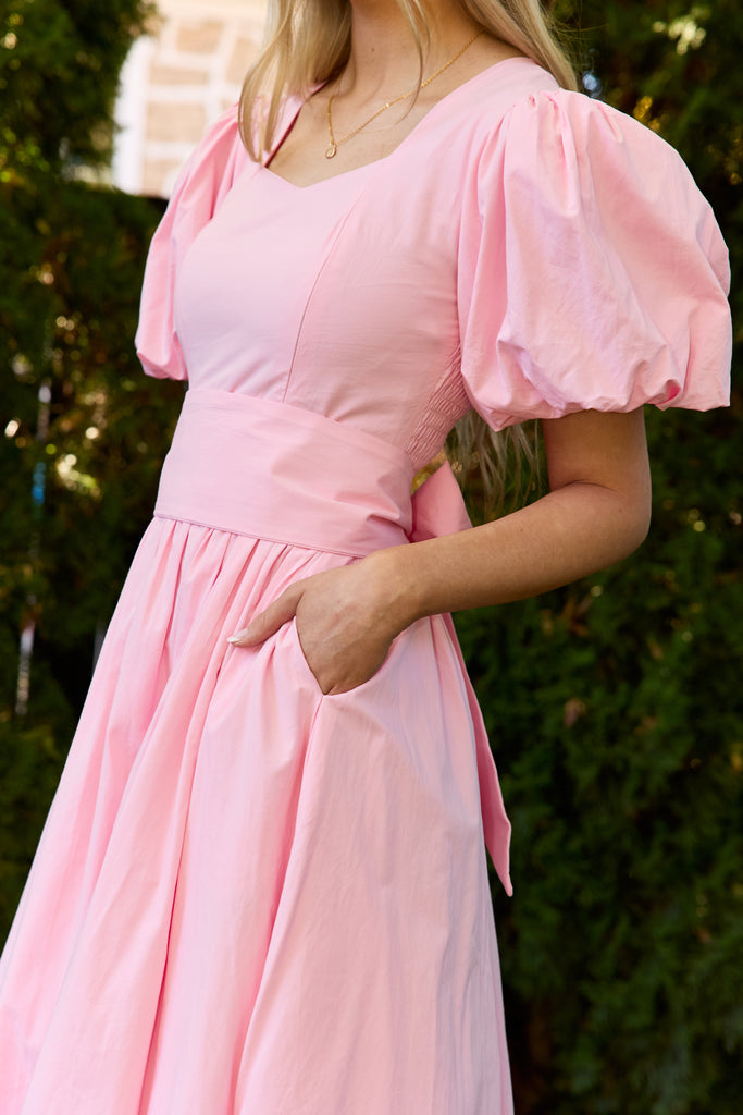 Pink dress with puff sleeves worn by a person, against a blurred green background - modest cotton knee-length dress nursing-friendly