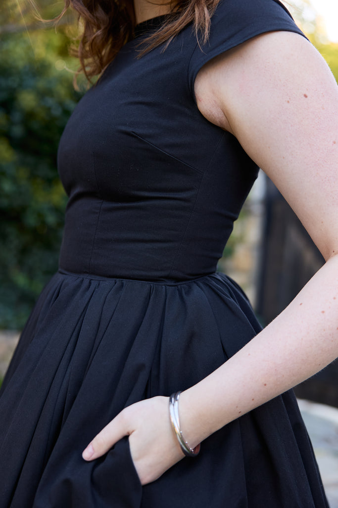 Woman wearing a black dress with a blurred background - black 50s fit and flare vintage midi 1950s inspired timeless for events holiday party retro tea-length