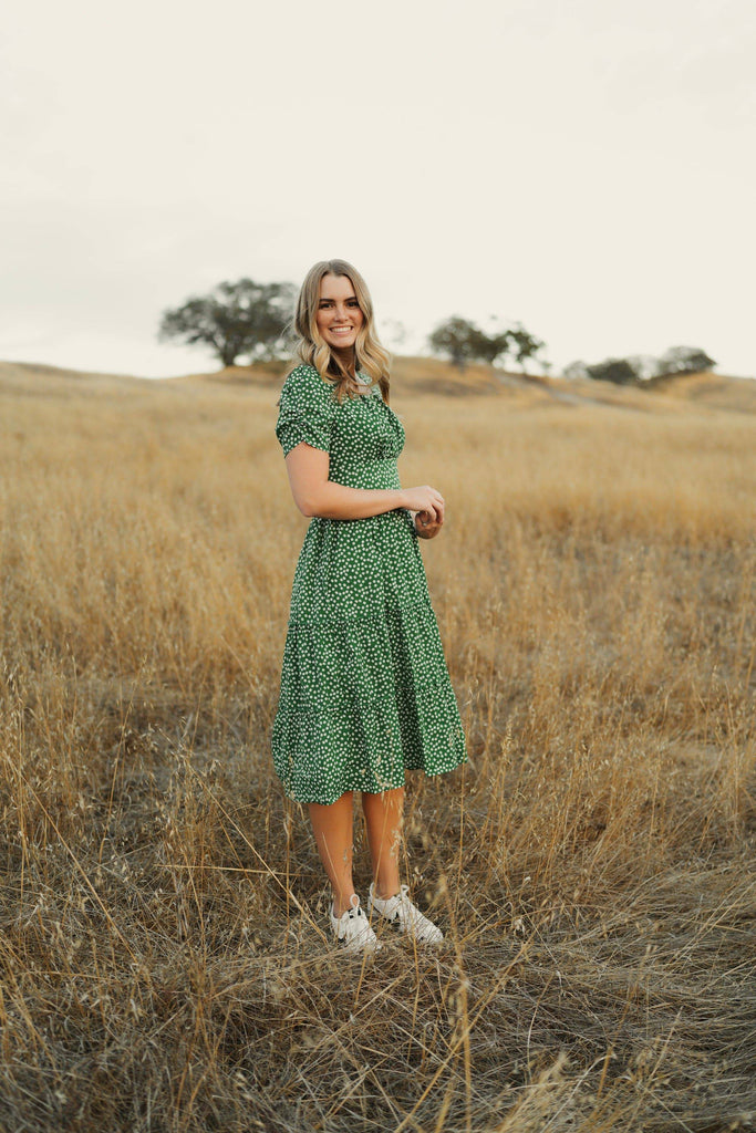girl in green midi dress standing in field